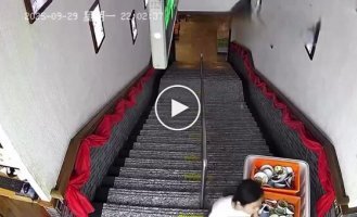 A girl tries to roll a container of dishes down the stairs