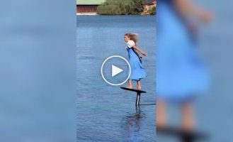Athlete in Bavarian dress flies over a lake on a hydrofoil