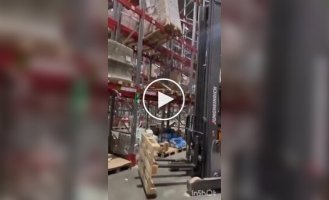 Работник склада аккуратно выровнял неустойчивый стеллаж с помощью погрузчика