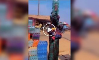 В Африке женщина поразила силой и ловкостью, унеся 8 упаковок напитков — 4 на голове и 4 в руках