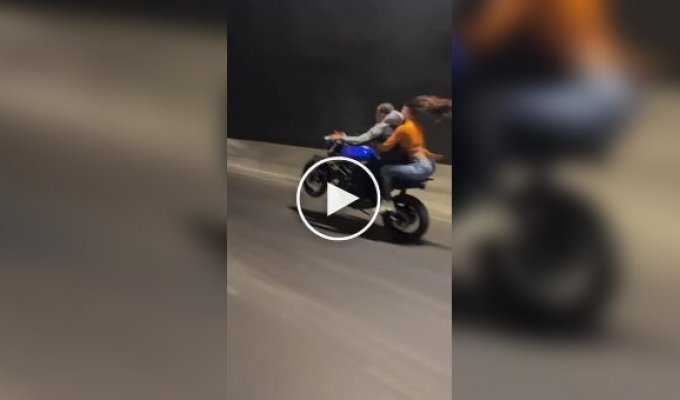 Biker rears up motorcycle with passenger on back
